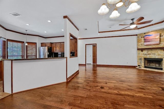 unfurnished living room with dark wood-type flooring, crown molding, a fireplace, and ceiling fan with notable chandelier