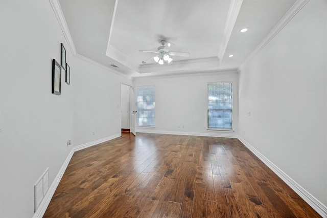 spare room featuring crown molding, a tray ceiling, dark wood-type flooring, and ceiling fan