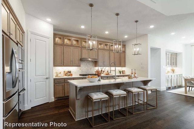 kitchen with sink, dark wood-type flooring, hanging light fixtures, and stainless steel appliances