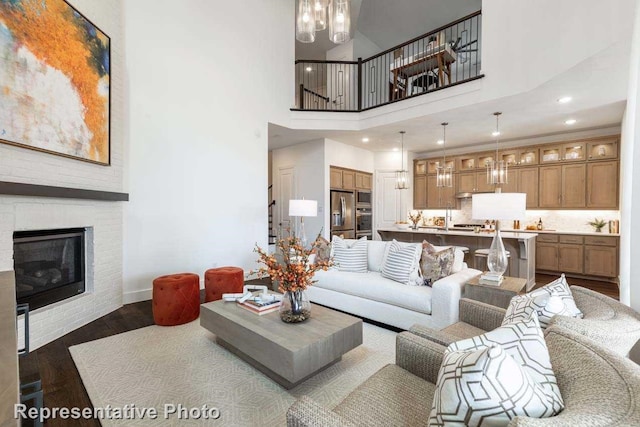 living room with dark wood-type flooring, a towering ceiling, and a fireplace