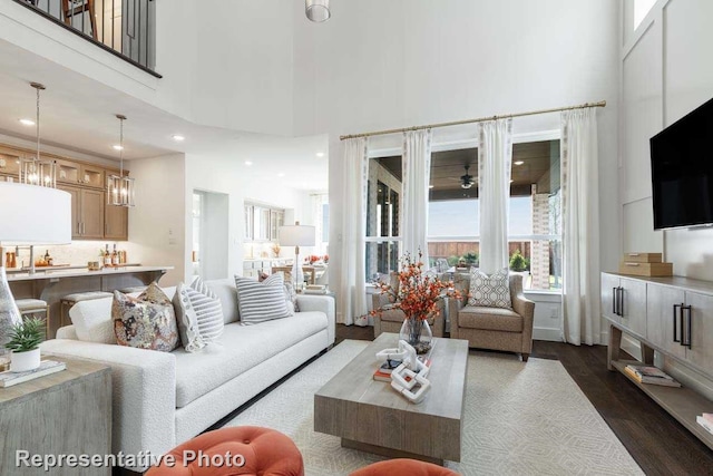 living room featuring a towering ceiling, dark hardwood / wood-style flooring, and ceiling fan with notable chandelier