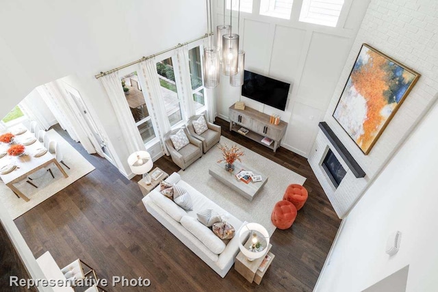 living room featuring a towering ceiling, dark wood-type flooring, and a healthy amount of sunlight