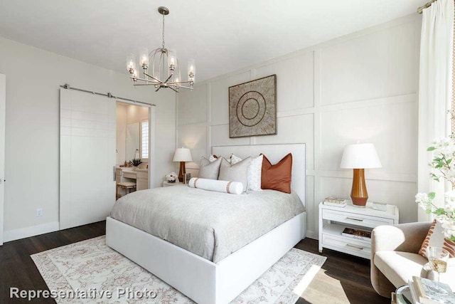 bedroom with dark hardwood / wood-style floors, an inviting chandelier, and a barn door