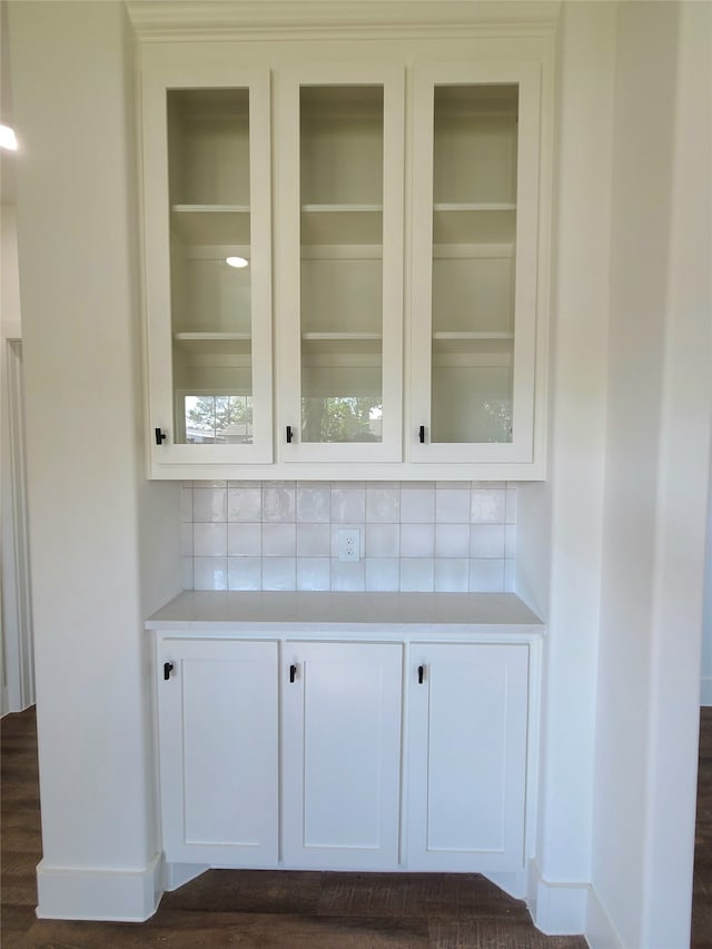 bar with white cabinets, backsplash, and dark hardwood / wood-style flooring