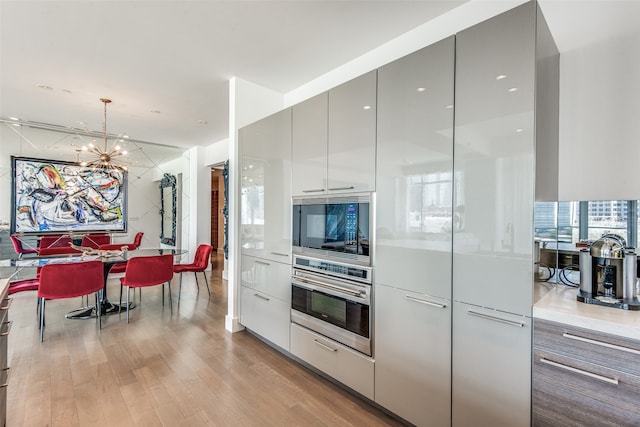 kitchen with oven, a notable chandelier, hanging light fixtures, and light hardwood / wood-style floors