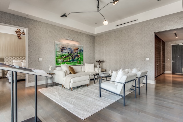 living room with a tray ceiling and dark hardwood / wood-style flooring