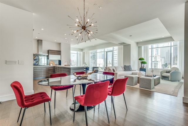 dining space featuring sink, light hardwood / wood-style floors, a wealth of natural light, and a chandelier