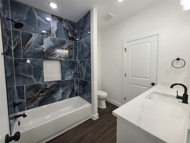 full bathroom with toilet, tiled shower / bath, hardwood / wood-style floors, and vanity