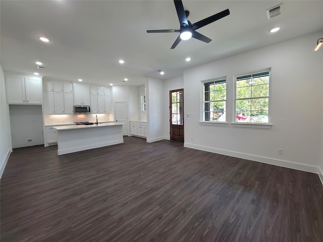 kitchen featuring a center island with sink, ceiling fan, white cabinetry, dark wood-type flooring, and sink