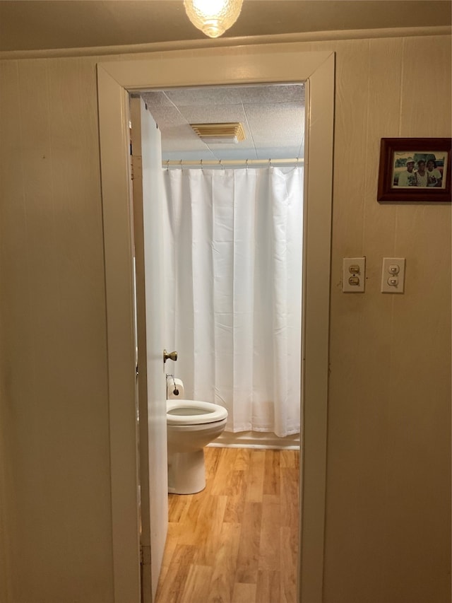 bathroom featuring curtained shower, hardwood / wood-style flooring, and toilet