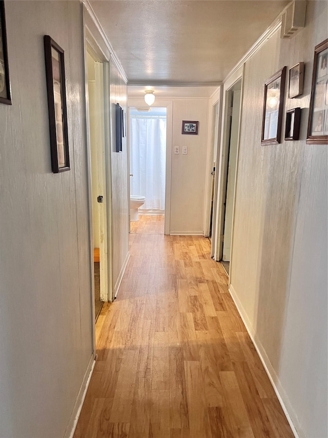 hallway with crown molding and light wood-type flooring