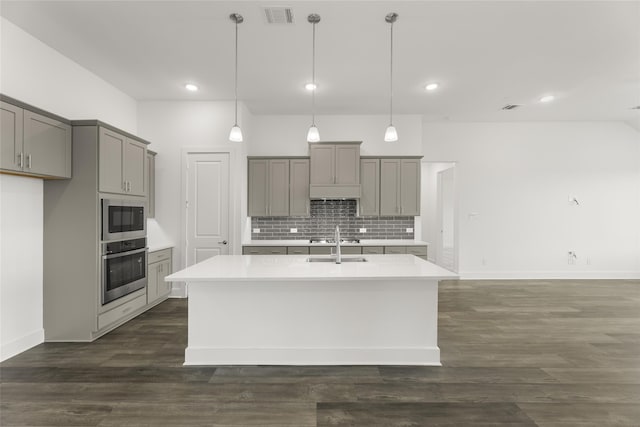 kitchen featuring gray cabinets, decorative light fixtures, a kitchen island with sink, and stainless steel appliances