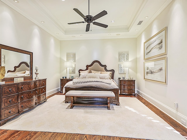 bedroom featuring crown molding, hardwood / wood-style flooring, a raised ceiling, and ceiling fan