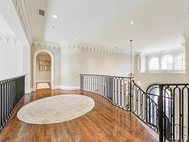 hall featuring ornamental molding, hardwood / wood-style flooring, and a chandelier