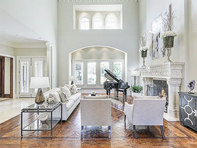 living room featuring crown molding, wood-type flooring, a high ceiling, and decorative columns