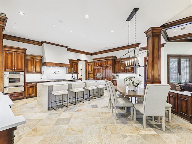 dining area with a notable chandelier, sink, ornate columns, and crown molding