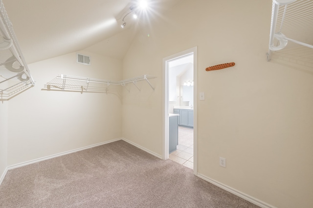 spacious closet with vaulted ceiling and light colored carpet