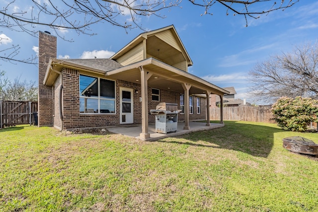 back of property featuring a yard, a patio, and a fire pit