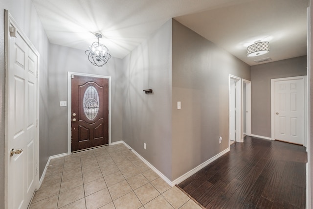 foyer entrance with light hardwood / wood-style flooring and a chandelier