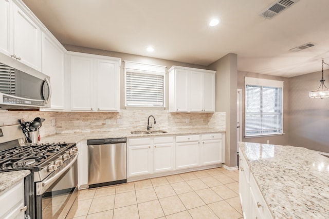 kitchen with backsplash, sink, decorative light fixtures, white cabinetry, and appliances with stainless steel finishes