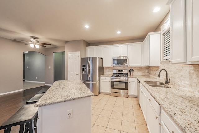 kitchen featuring white cabinetry, light stone countertops, stainless steel appliances, and sink