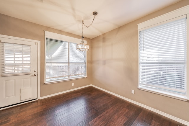 unfurnished dining area with an inviting chandelier and dark wood-type flooring