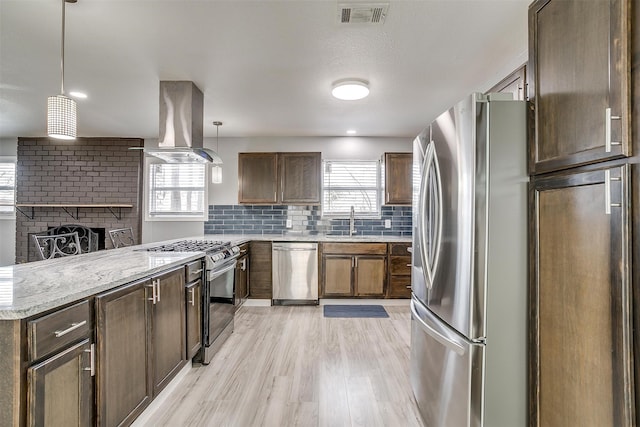 kitchen featuring a wealth of natural light, island exhaust hood, appliances with stainless steel finishes, and decorative light fixtures