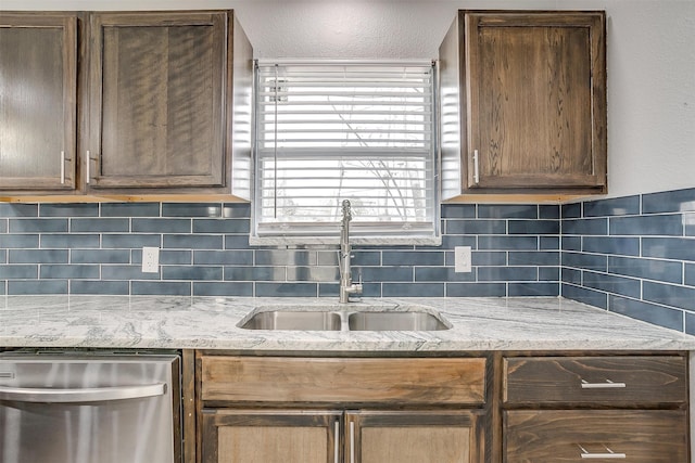 kitchen featuring light stone counters, backsplash, a textured ceiling, dishwasher, and sink