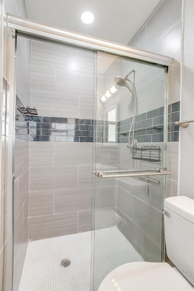 bathroom featuring toilet and a shower with shower door