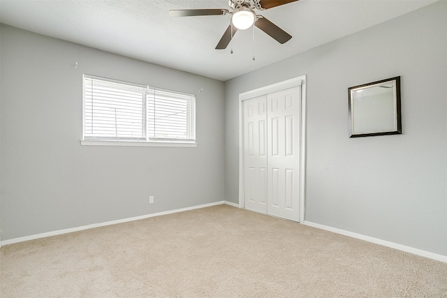 unfurnished bedroom featuring light colored carpet, a closet, and ceiling fan