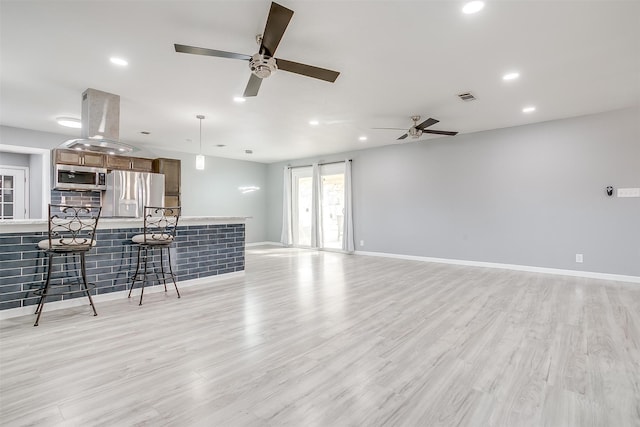 living room featuring bar area, light wood-type flooring, and ceiling fan