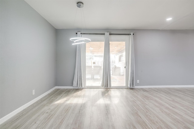 unfurnished room featuring light hardwood / wood-style floors and a chandelier