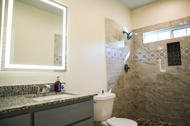 bathroom featuring toilet, vanity, and a tile shower