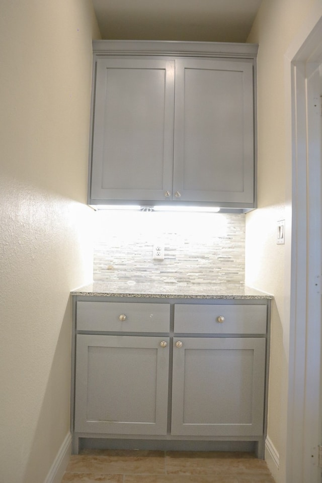 bar with gray cabinets and tasteful backsplash