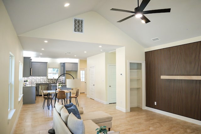 living room featuring ceiling fan, high vaulted ceiling, and light hardwood / wood-style flooring