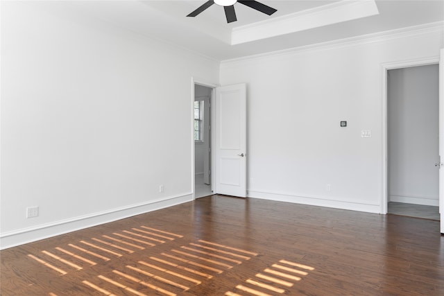 spare room featuring a tray ceiling, crown molding, ceiling fan, and dark hardwood / wood-style floors