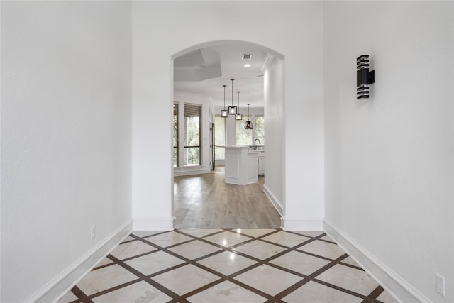 corridor featuring sink and ornamental molding