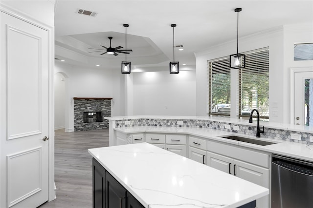 kitchen featuring white cabinets, a tray ceiling, sink, dishwasher, and a center island