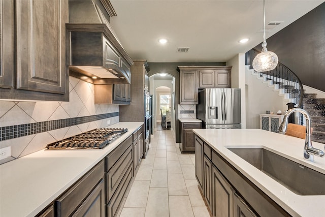 kitchen featuring arched walkways, stainless steel appliances, light countertops, visible vents, and a sink