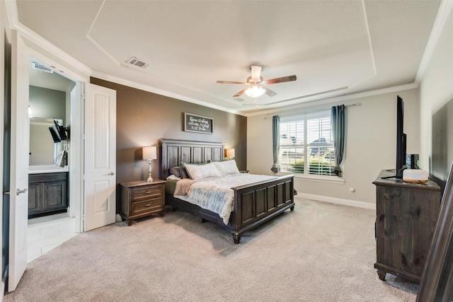 bedroom with ensuite bathroom, ornamental molding, light colored carpet, a raised ceiling, and ceiling fan