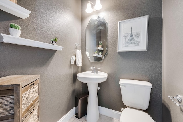 bathroom featuring toilet, baseboards, and a textured wall