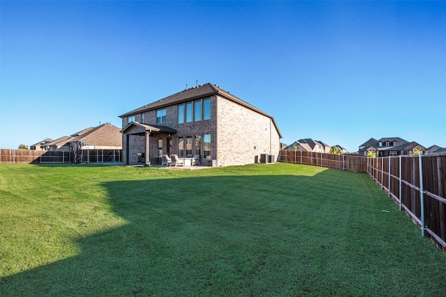 rear view of house featuring brick siding, a lawn, and a fenced backyard