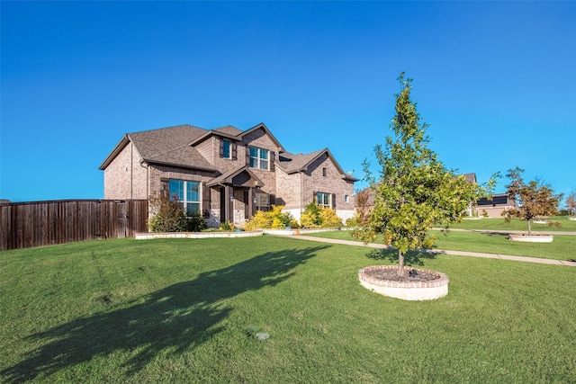 view of front of home featuring a shingled roof, fence, a front lawn, and brick siding