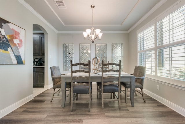 dining room featuring a chandelier, a tray ceiling, hardwood / wood-style flooring, and ornamental molding