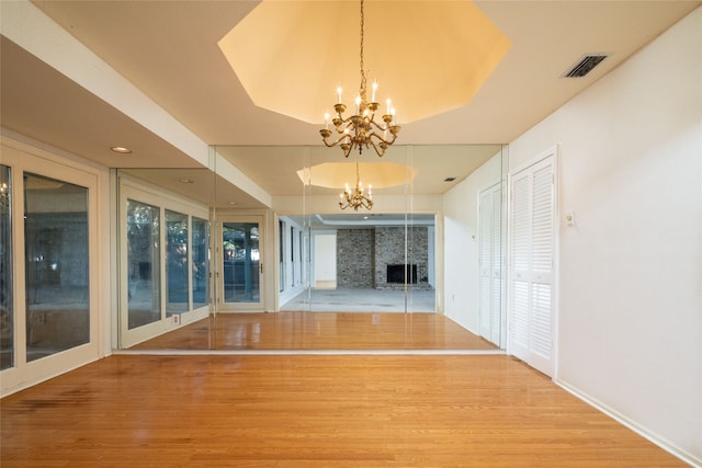 unfurnished living room featuring an inviting chandelier, hardwood / wood-style floors, and a tray ceiling