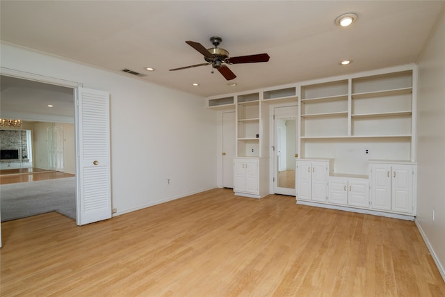 unfurnished bedroom with a fireplace, light hardwood / wood-style floors, and ceiling fan