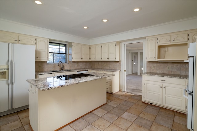 kitchen featuring white fridge with ice dispenser, light stone countertops, sink, crown molding, and a center island