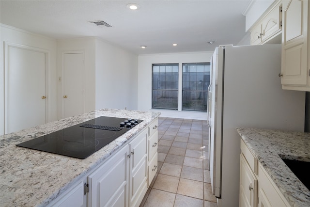 kitchen with black electric cooktop, white fridge, light stone counters, and light tile patterned floors