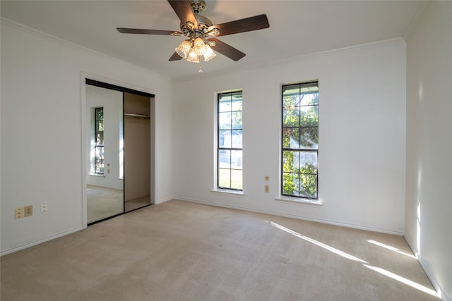 unfurnished bedroom featuring light carpet, a closet, ornamental molding, and ceiling fan