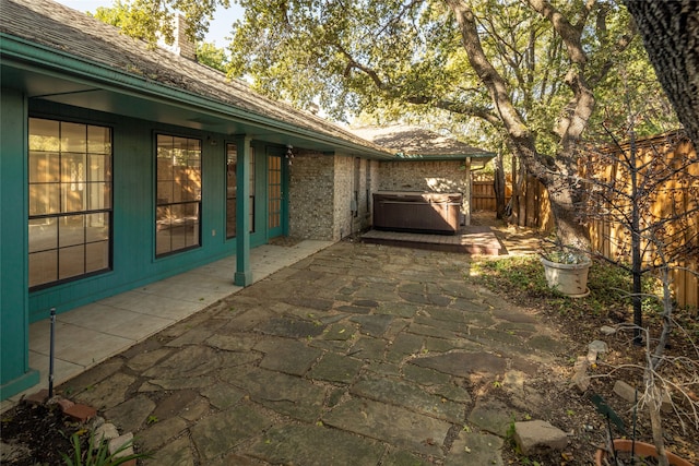 view of home's exterior with a hot tub and a patio